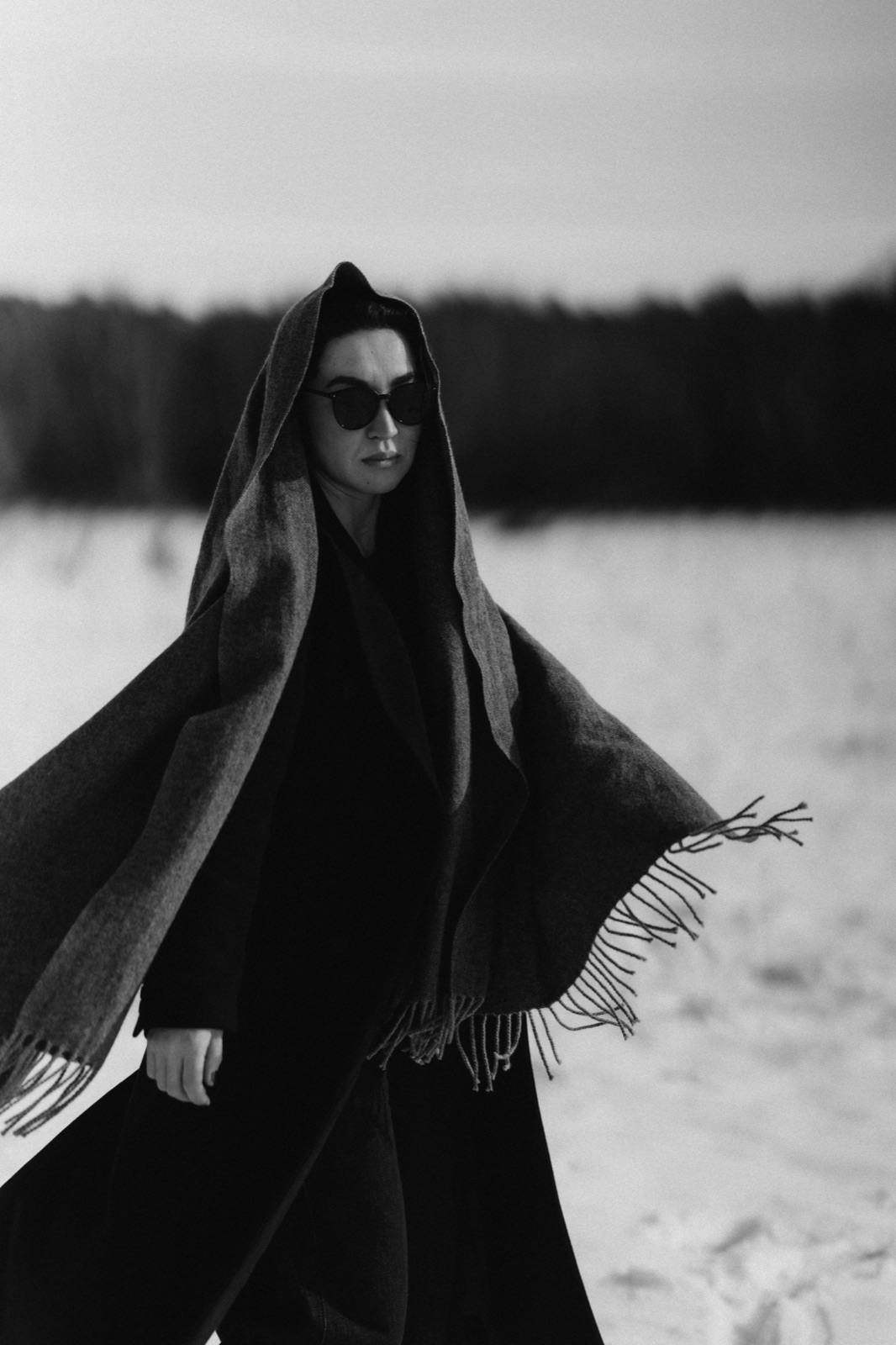Frau mit Sonnenbrille und Kapuzenschal im Schnee, Schwarz-Weiß