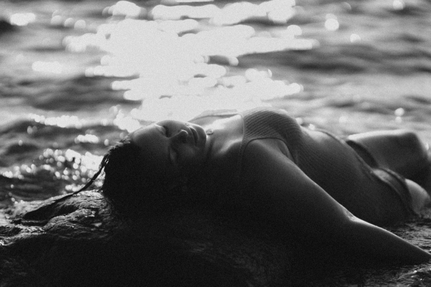 Frau ruhend am Wasser im Gegenlicht, Schwarz-Weiß